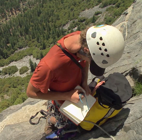 A scientist takes notes from a cliffside perch in Yosemite National Park