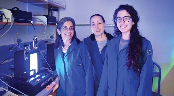 Sabeeha Merchant and other lab members standing in a lab next to a bioreactor.