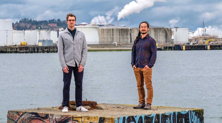 Nicholas Depsky (left) and Seigi Karasaki stand near the Harbor Channel in Richmond, California, where numerous industrial facilities may be impacted by sea-level rise.
