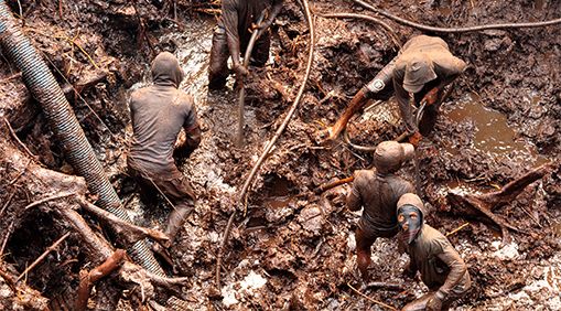 Miners use high-pressure hoses to break down the earth and dredge it up to find gold flakes.