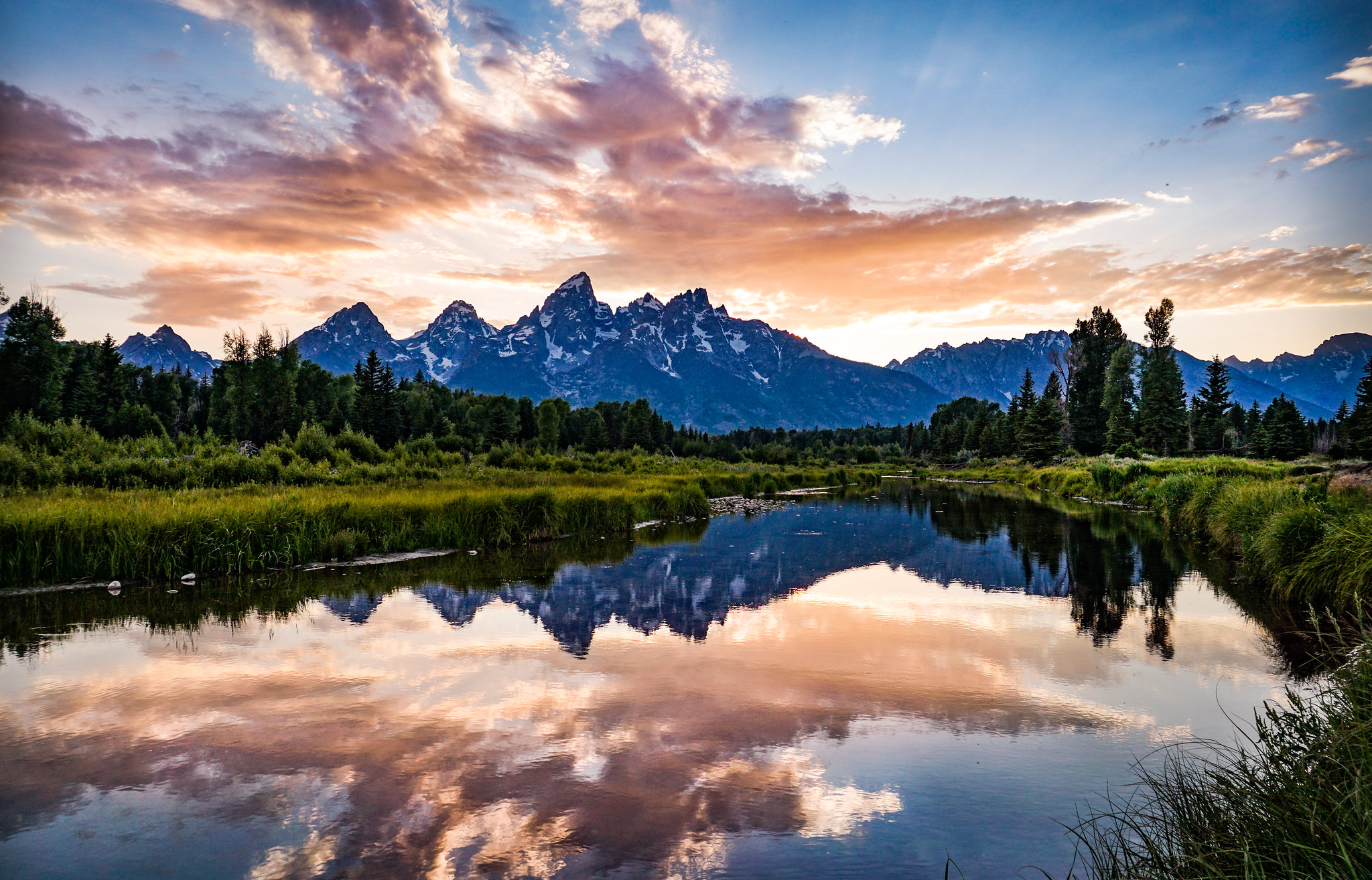 A colorful sky over mountains, reflected in the lake in the foreground