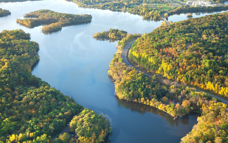 Image of large river/body of water surrounded by greenery 