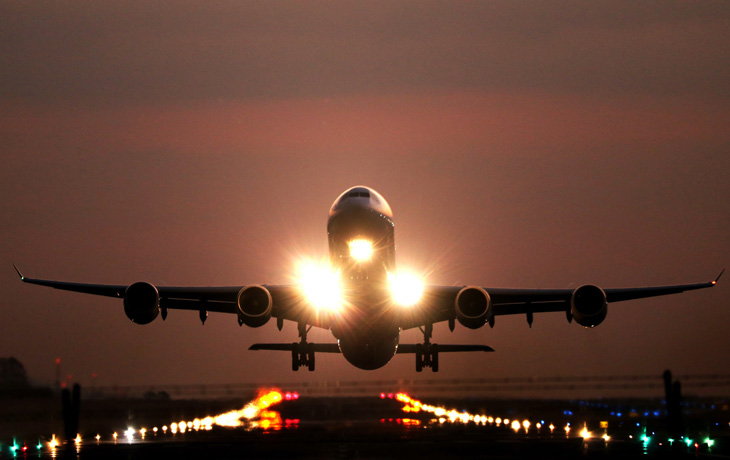 A plane takes off from a runway at dusk.