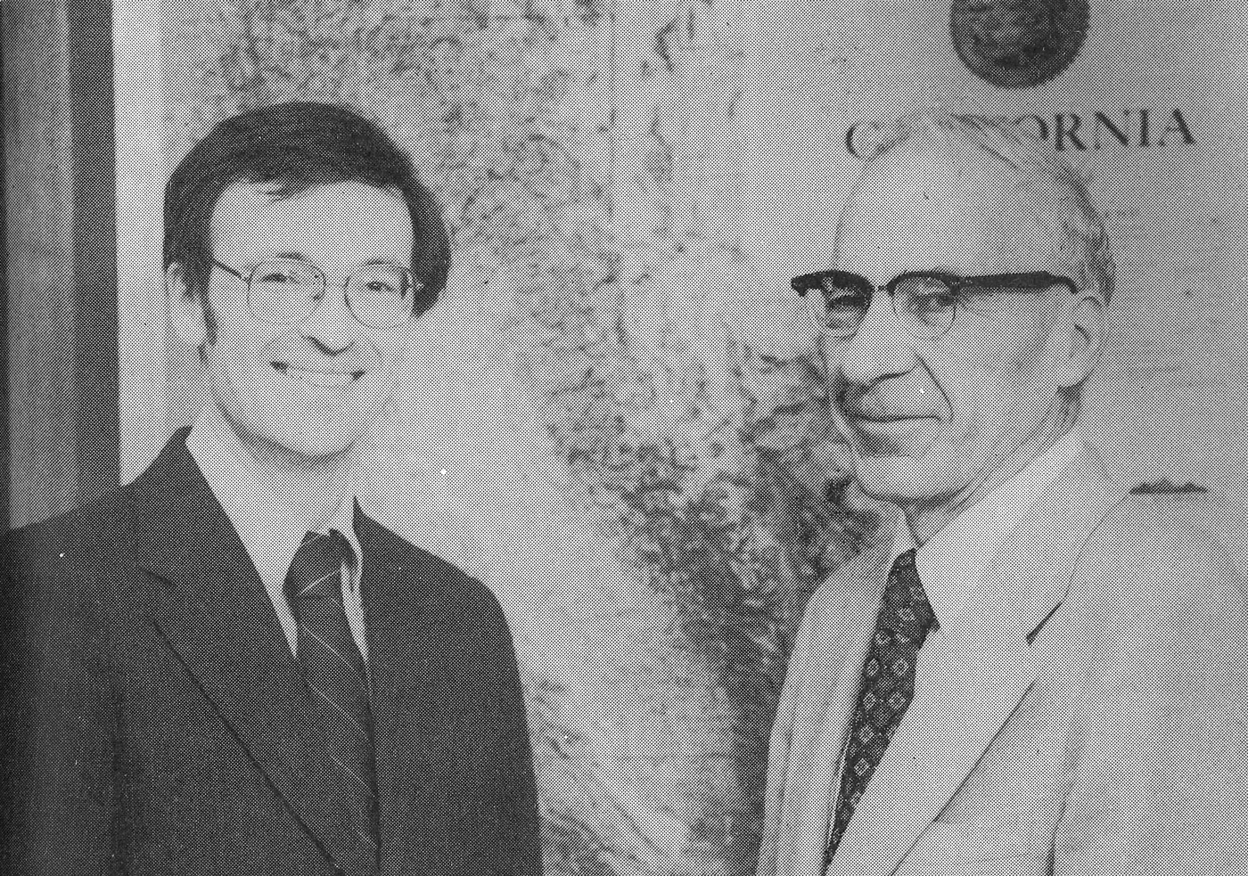 A black and white photo of two men smiling at the camera.