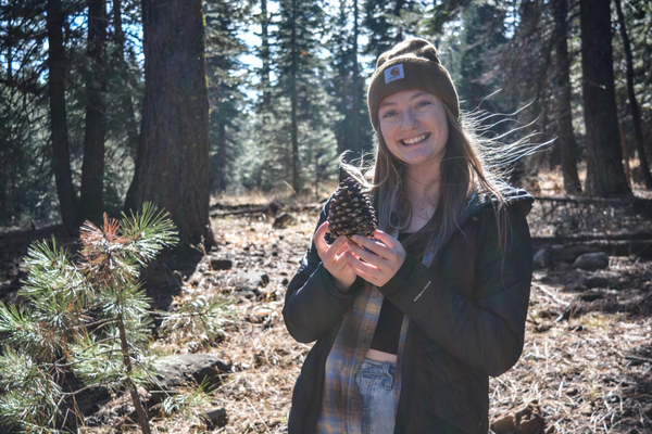 Ashlyn Olah in a forest holding a pine cone