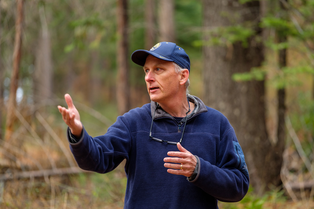 A photo of a man in a blue hat in a wooded environment.