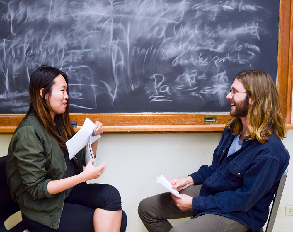Two students talking in front of a chalkboard