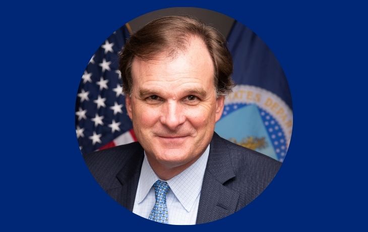 A graphic features a circular photo of a man in a suit looking at the camera.