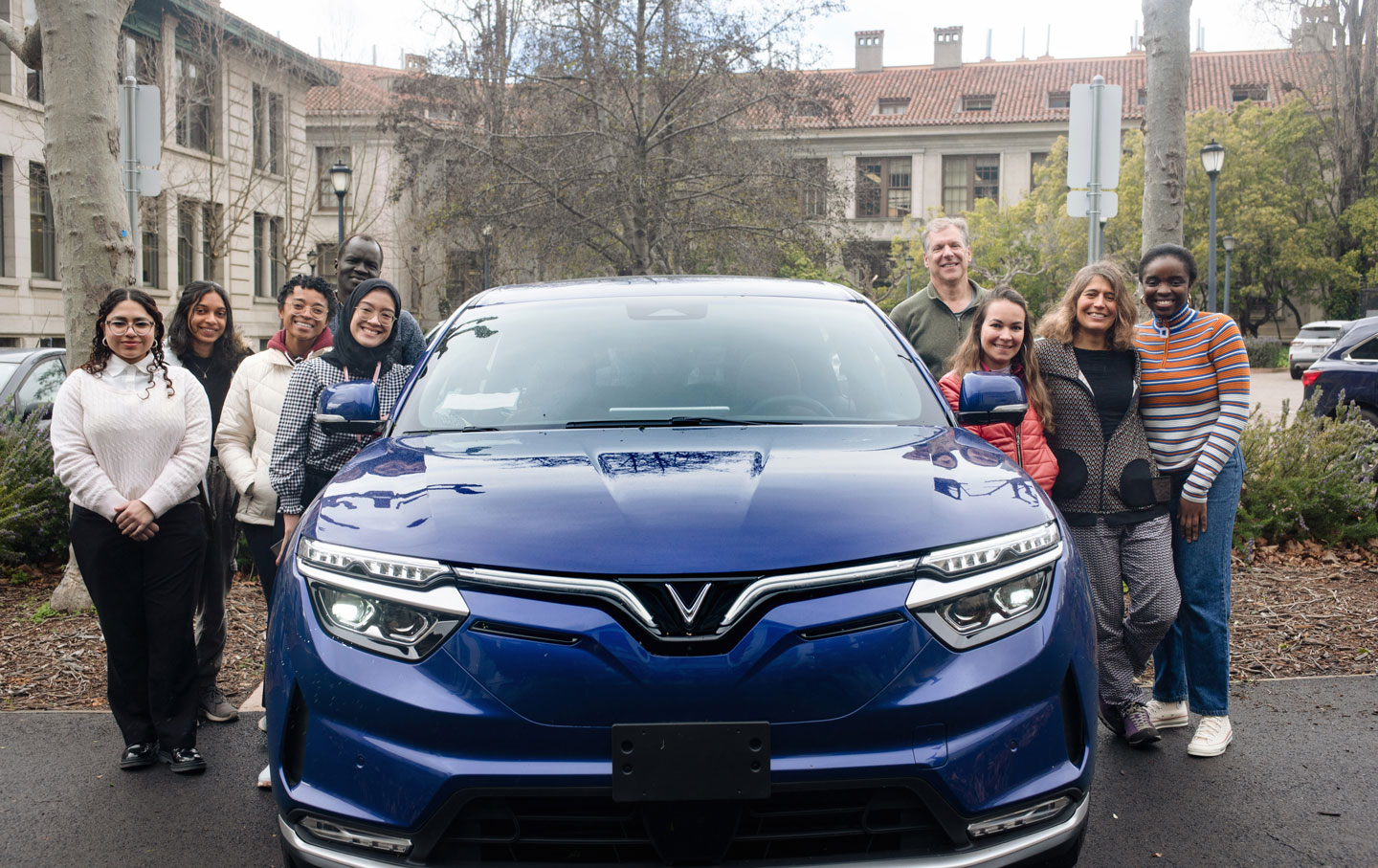 People gathered around a blue electric vehicle.