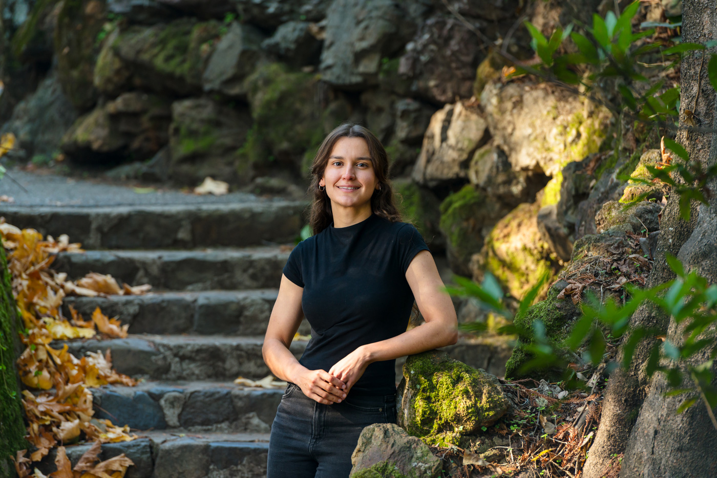 A photo of a woman standing in front of stone stairs in a natural environment.