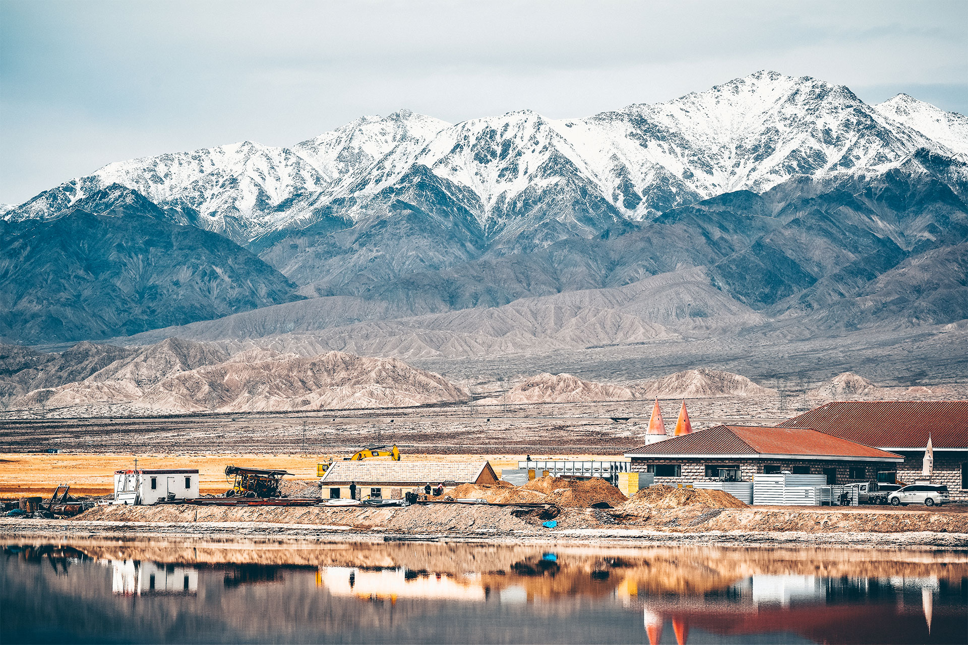 Mountains in Tibet with buildings and a body of water in the foreground