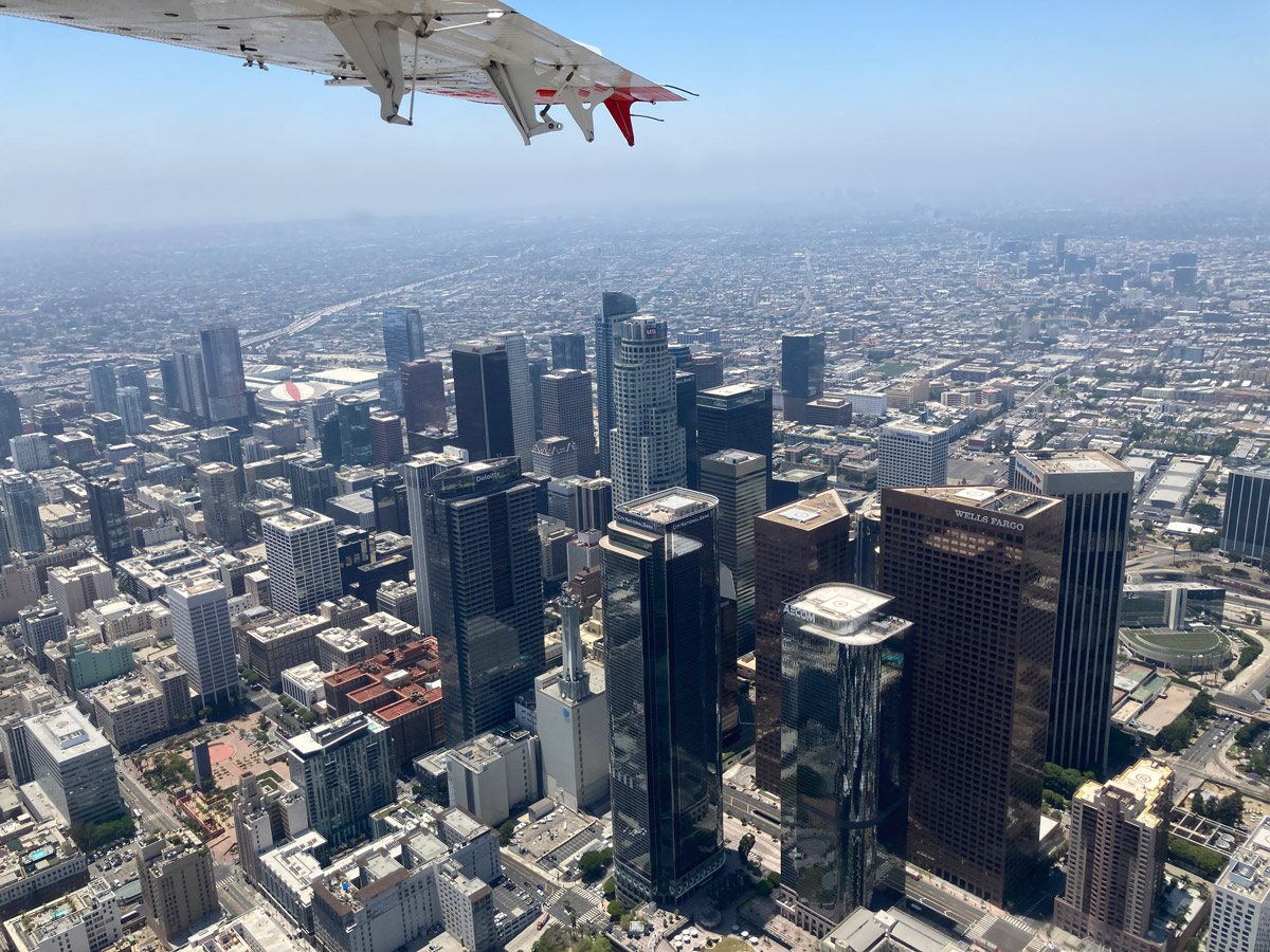 A photo that shows an aerial view of the buildings in downtown Los Angeles along with a partial view of a plane wing.