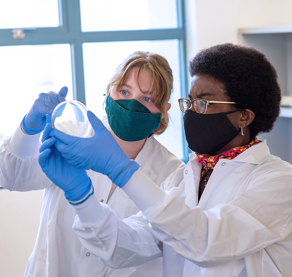 Two researchers wearing masks holding up a petri dish