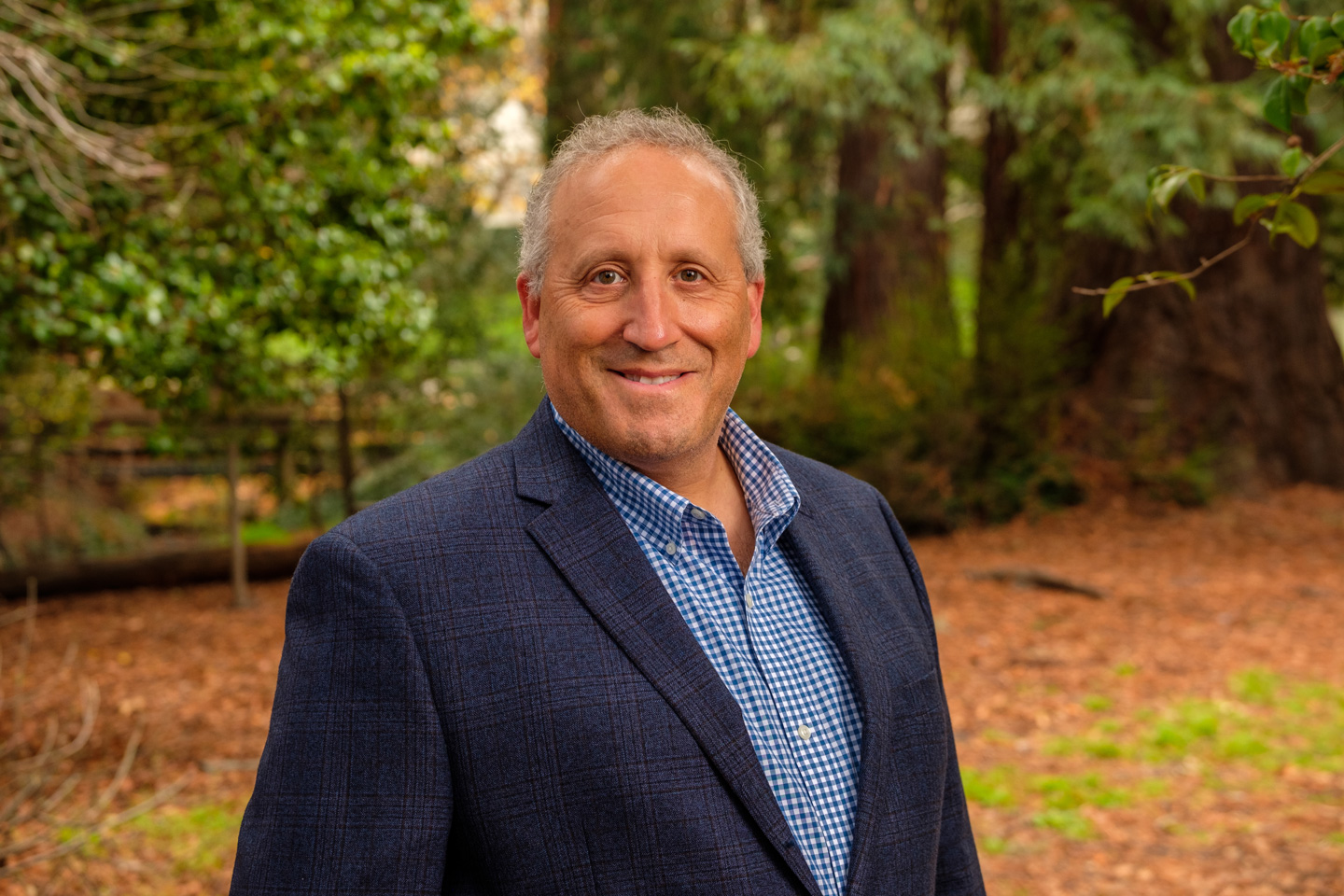 A photo of Professor Allen Goldstein smiling at the camera against a wooded backdrop.