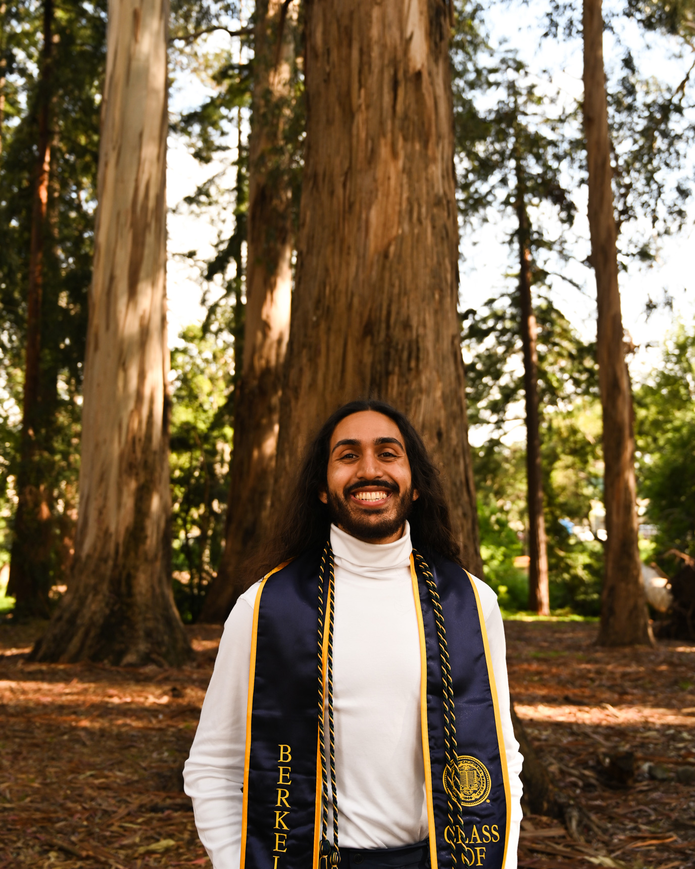 A graduation photo of Wanees Hannan in front of eucalyptus trees on the UC Berkeley campus.