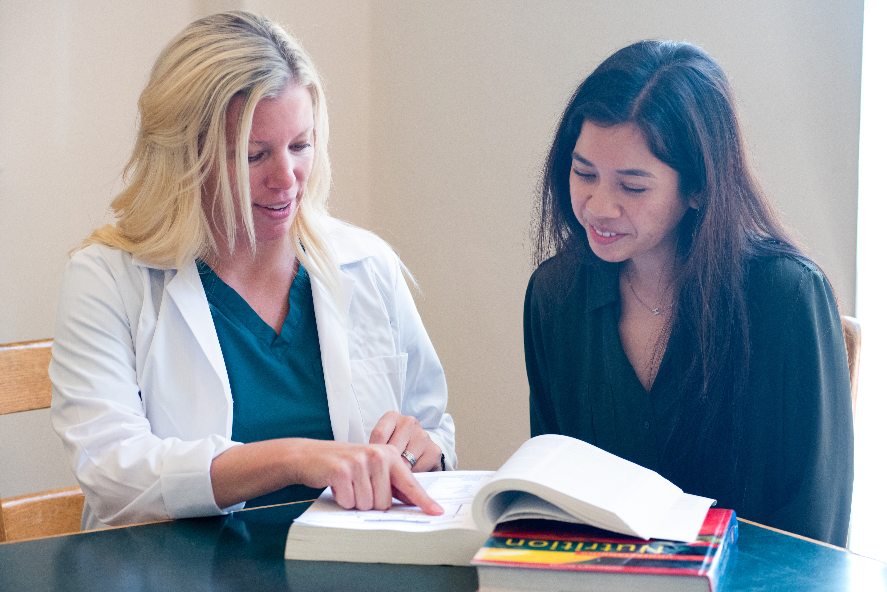 An instructor, Susie and a student reading a book.