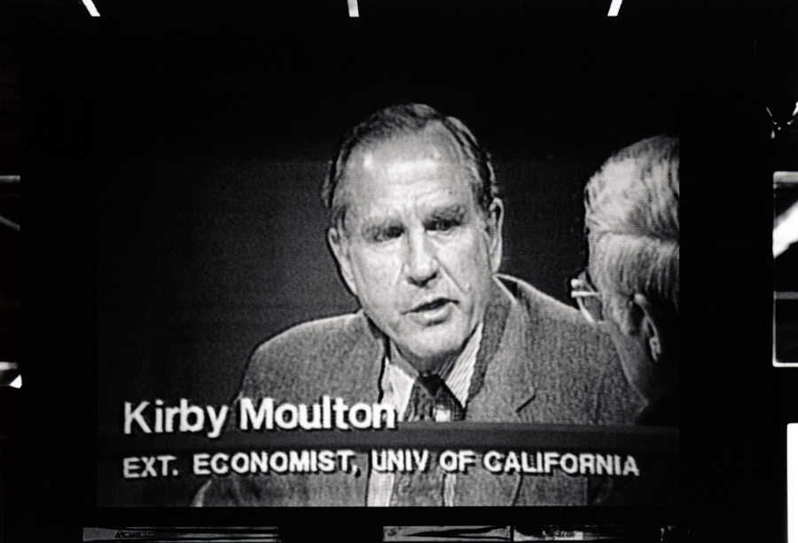 A photo of a man on a TV screen with text that reads: Kirby Moulton, extension economist