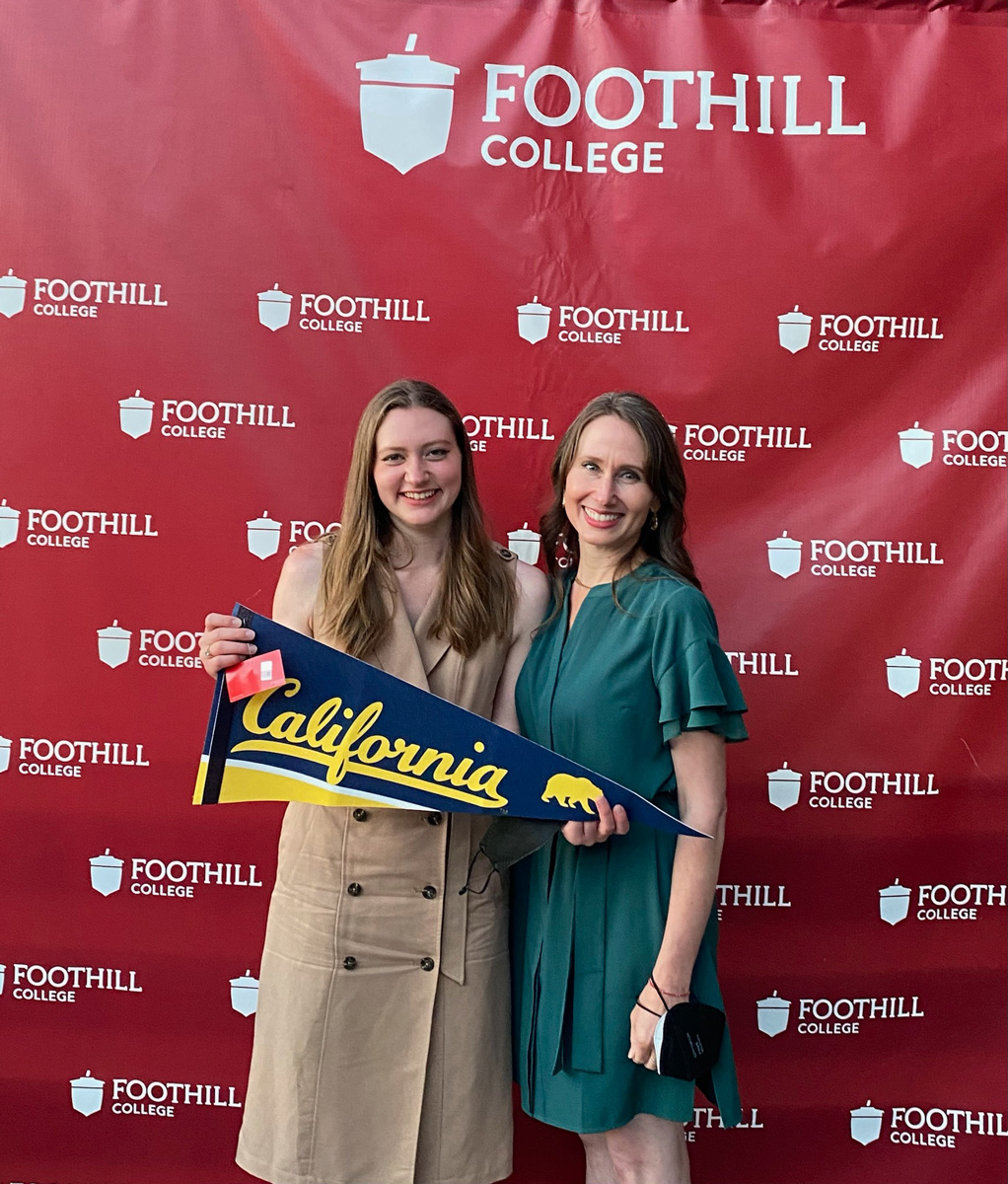 A photo of two women holding a a Cal pennant in front of sign reading Foothill College