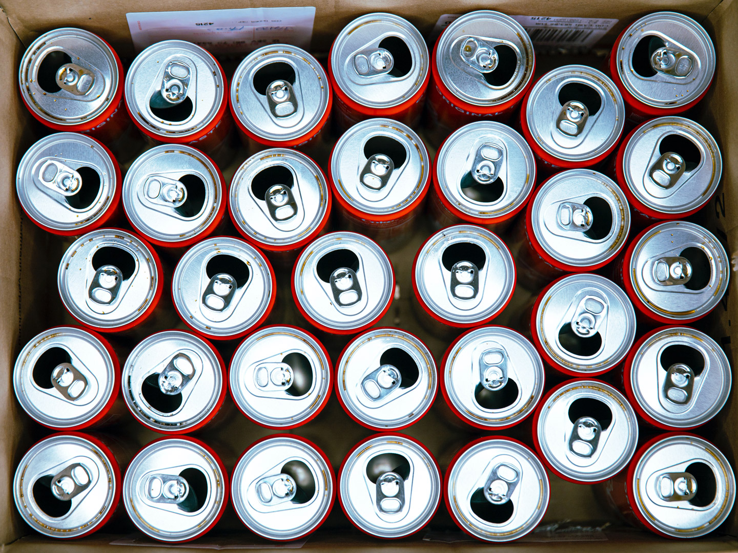 A picture of empty soda cans in a cardboard box.