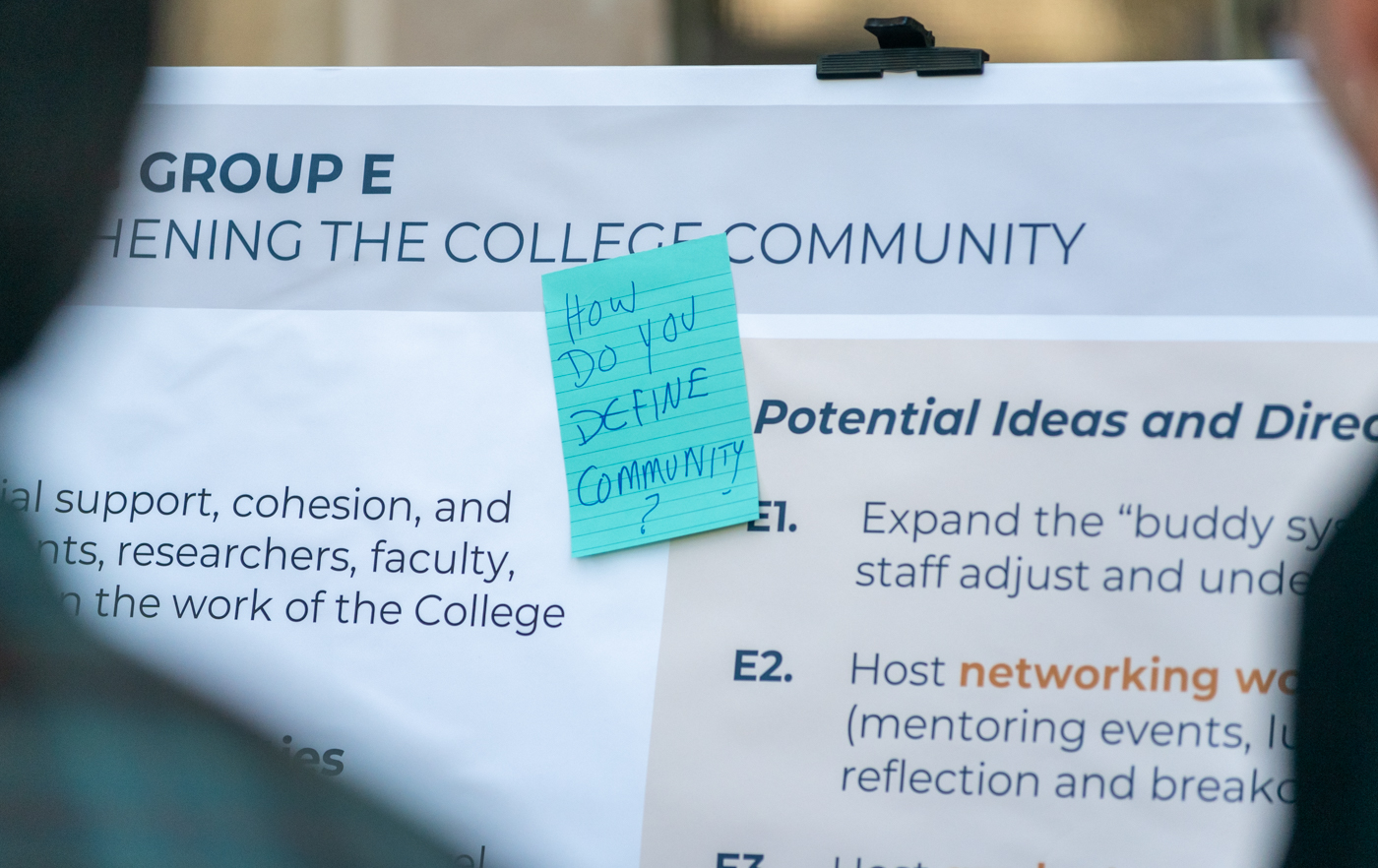 A sticky note attached to a planning board asks attendees how they define community.