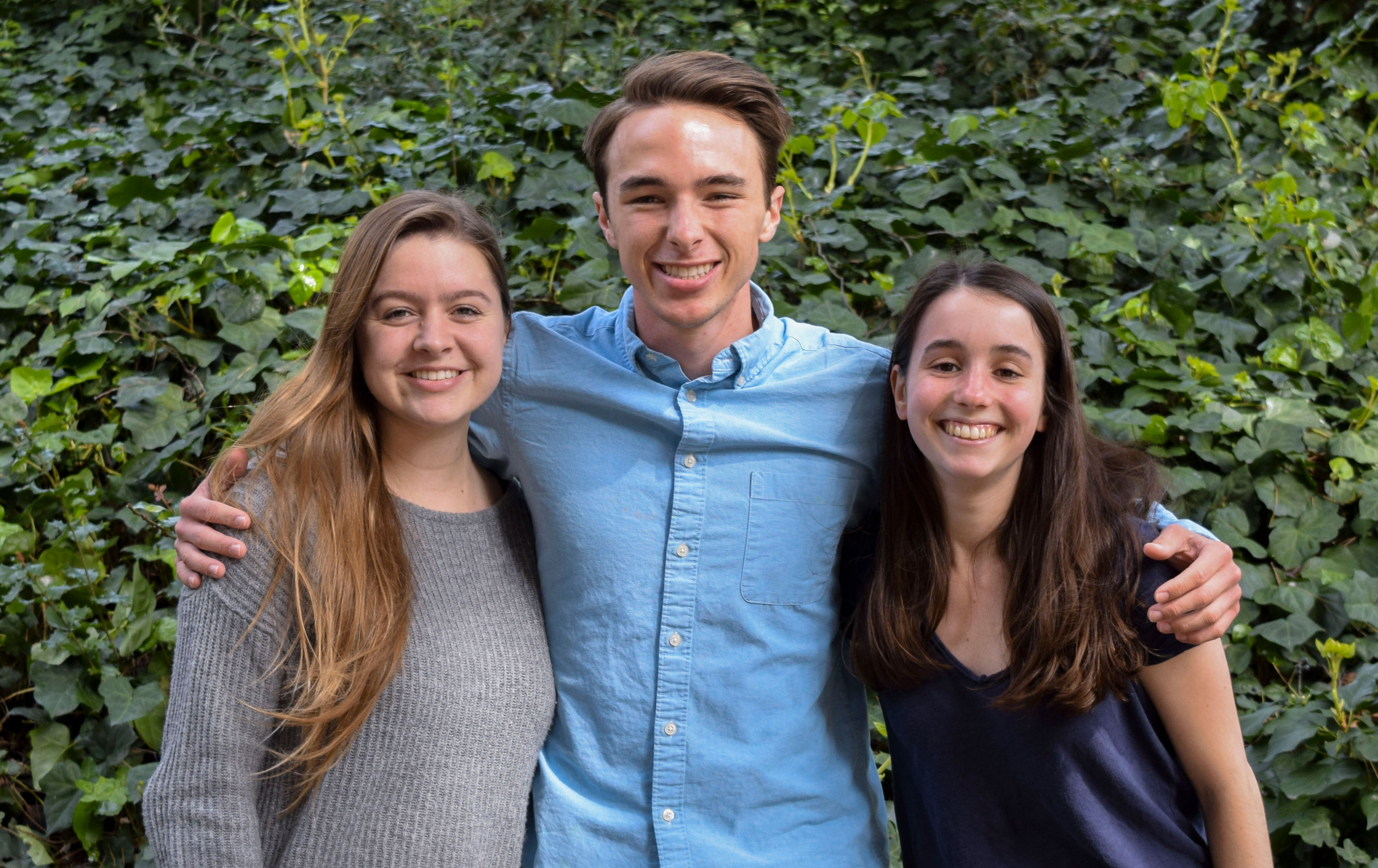 Three students standing together and smiling at camera