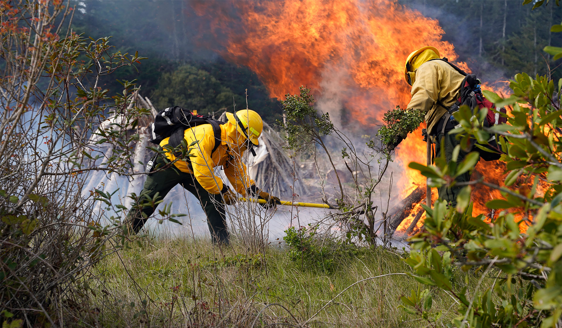 People in yellow fire protective gear working near a fire