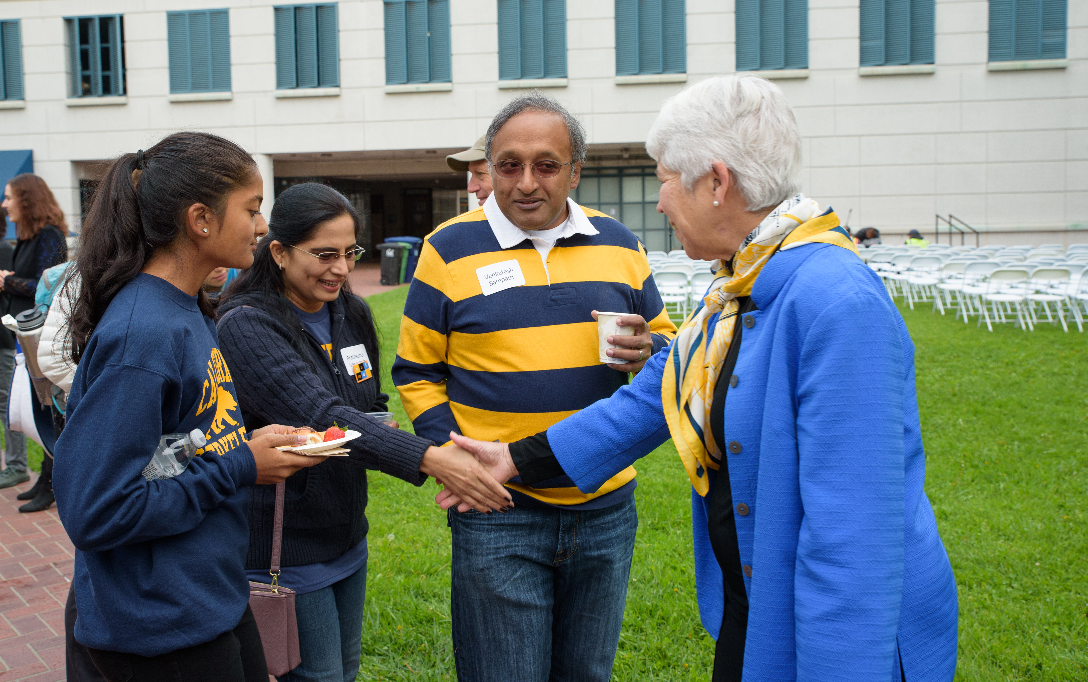 Chancellor Carol Christ shaking hands with student and parents at homecoming