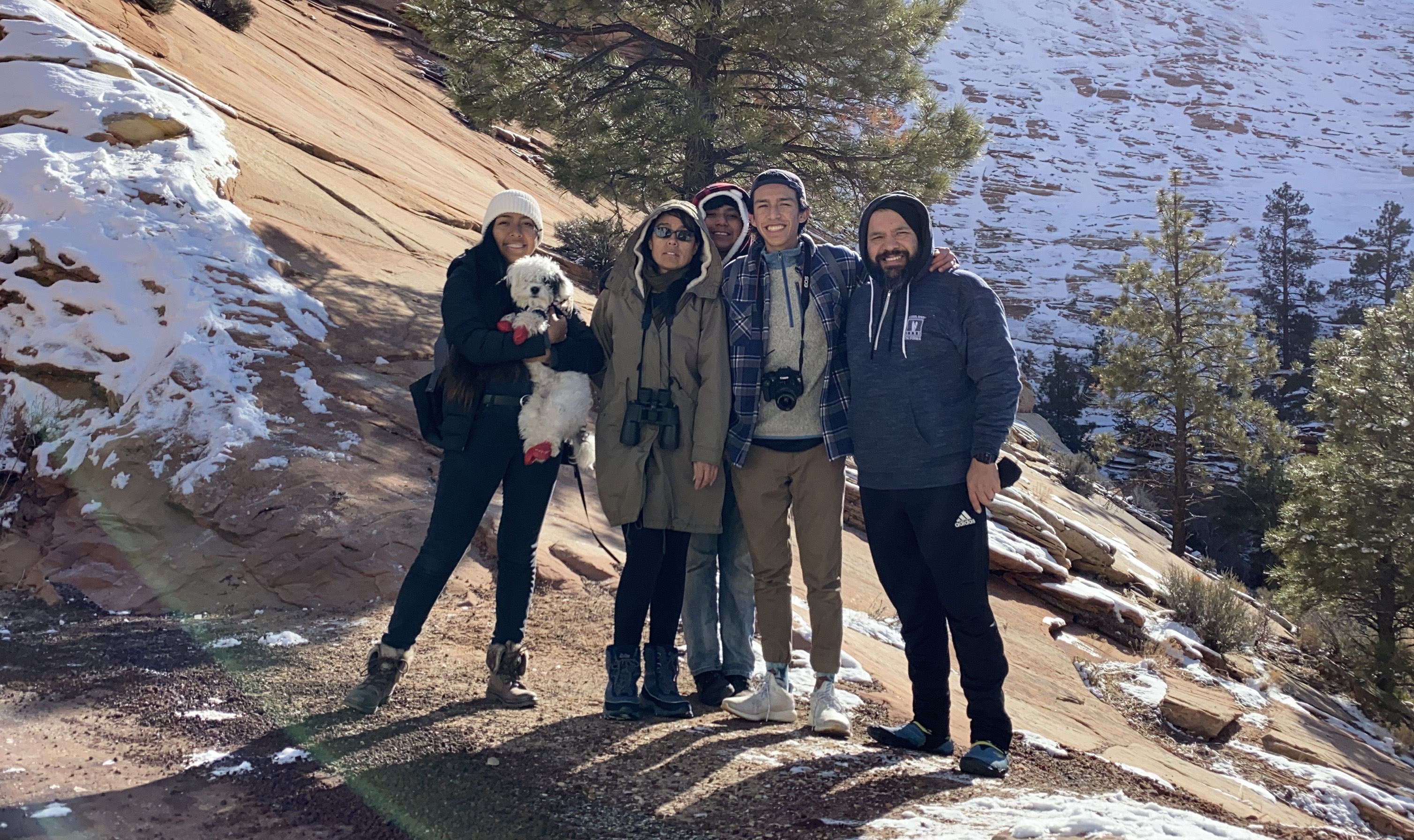 Isaac Aguilar poses with people and a dog on a snowy mountain