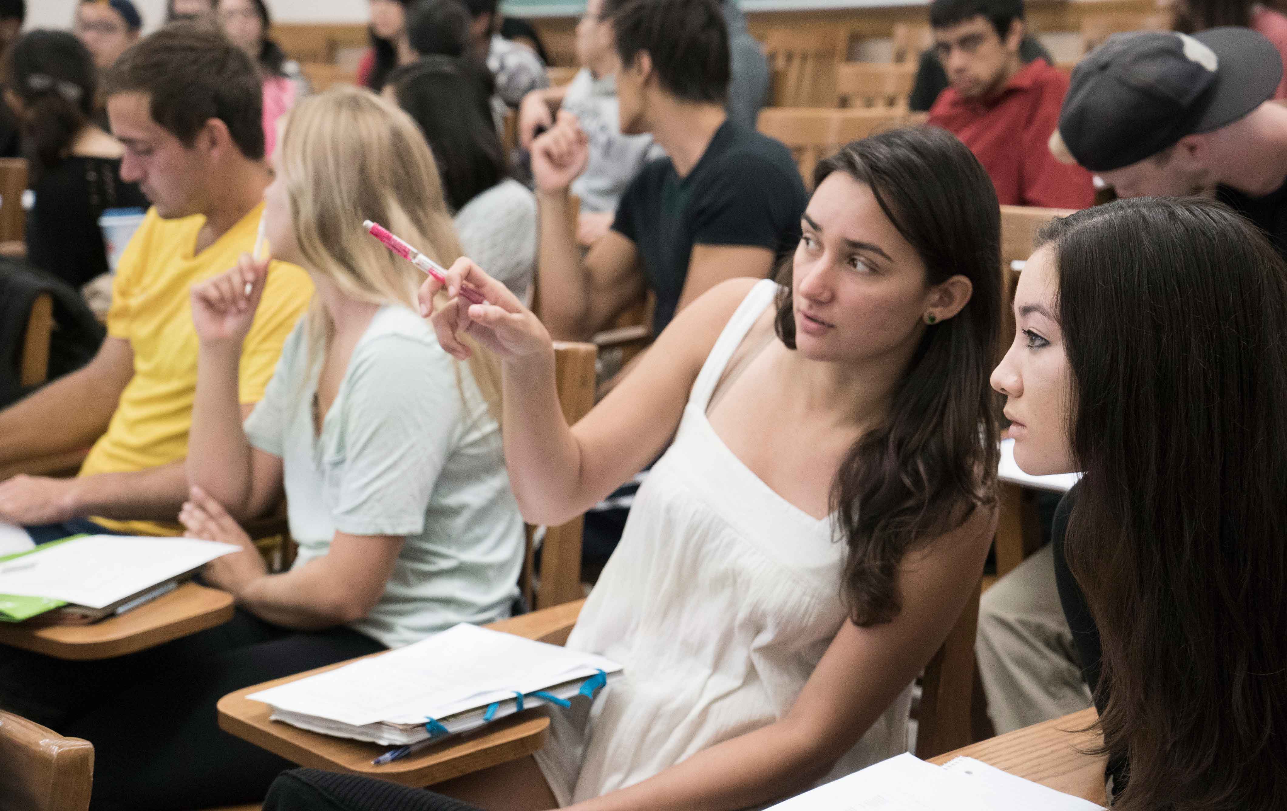 Two female students watch a lecture and point at the board