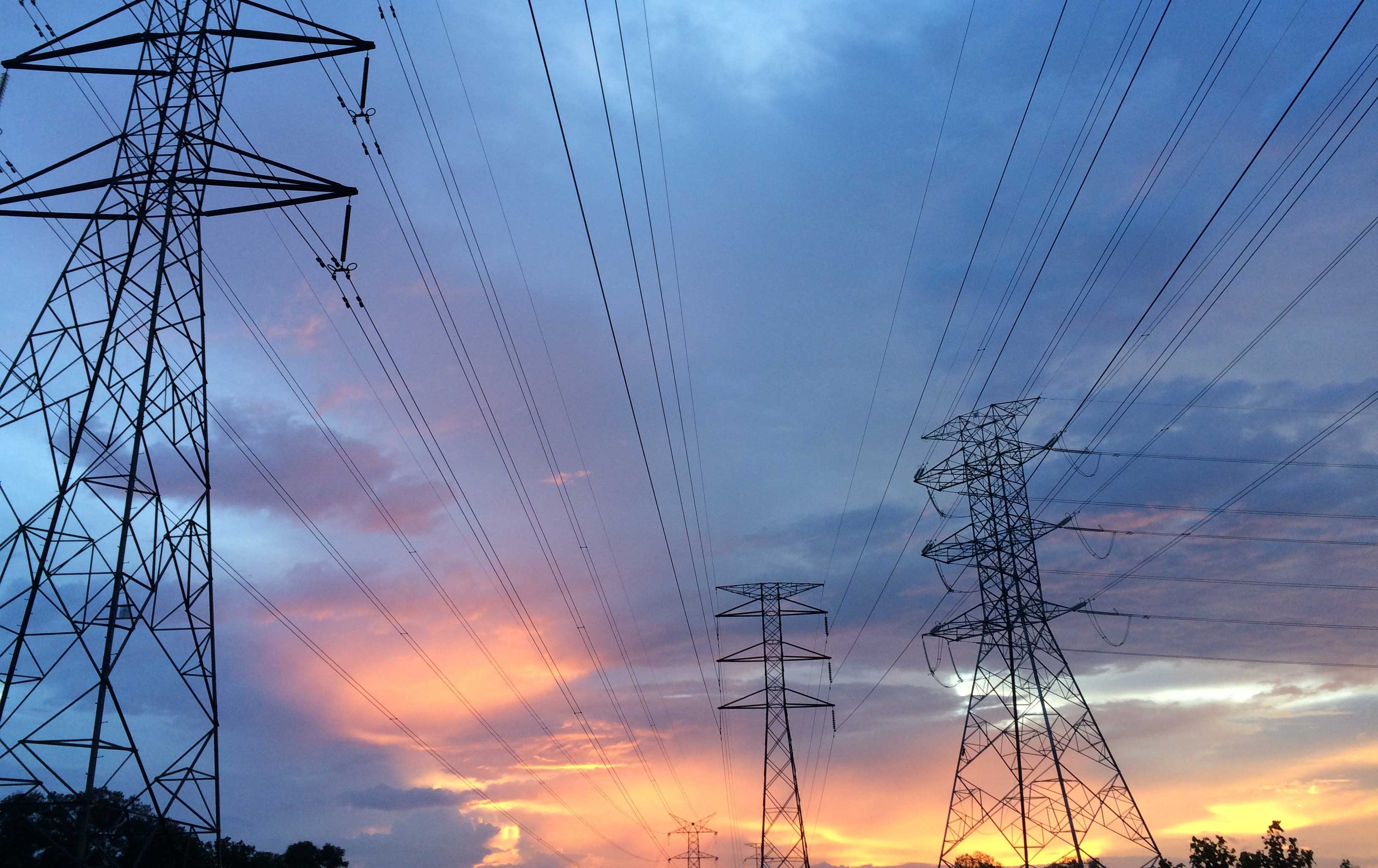 A colorful sunset with electrical grid towers in the foreground