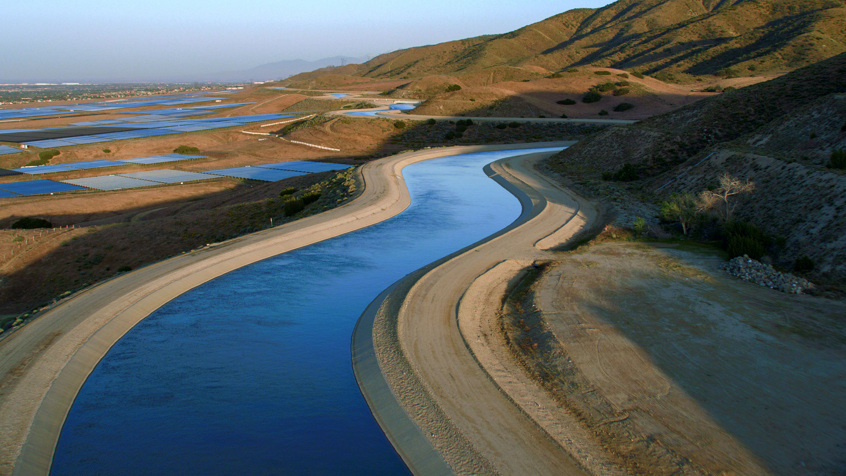 Blue water curving through a brown landscape in an aquaduct