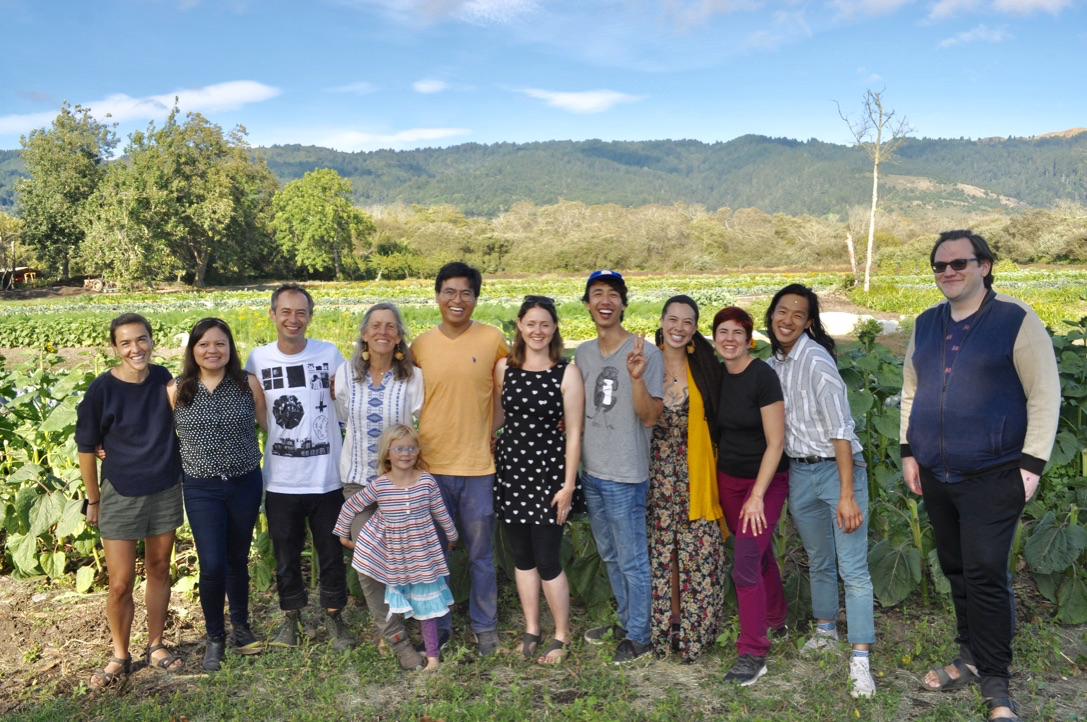 Group of people standing in a field on a farm. 