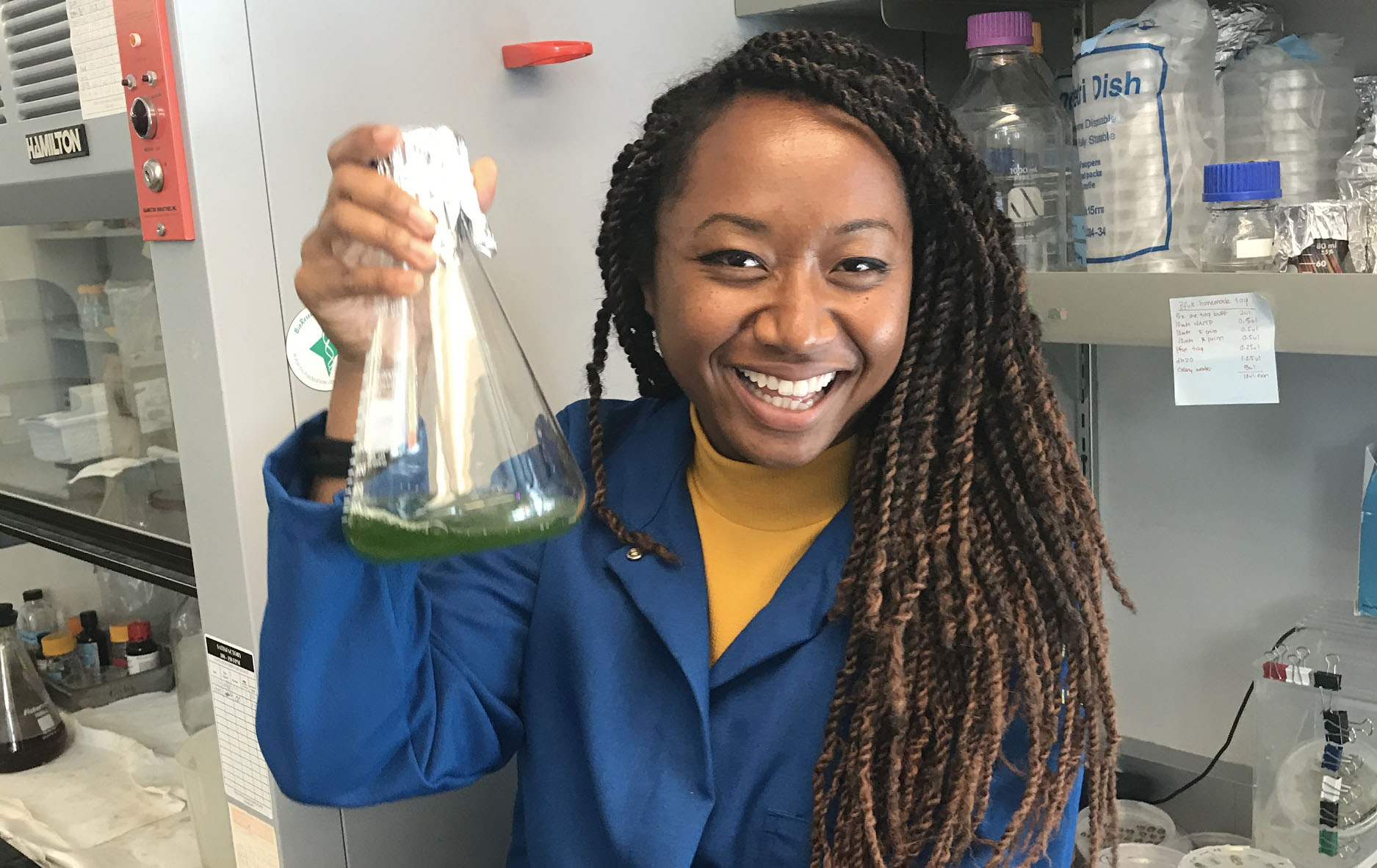 Thien Crisanto holds up a flask of algae 