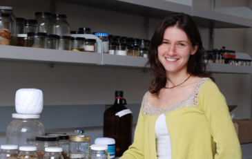 Bree Rosenblum stands next to jars in a lab