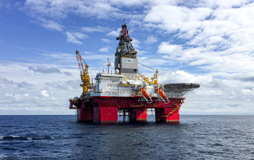An oil platform rig sits in the middle of the ocean.
