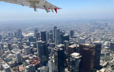 A photo that shows an aerial view of the buildings in downtown Los Angeles along with a partial view of a plane wing.