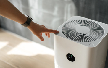 A photo of a person's hand turning on a white air purifier.