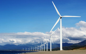 A series of wind turbines line a coast.