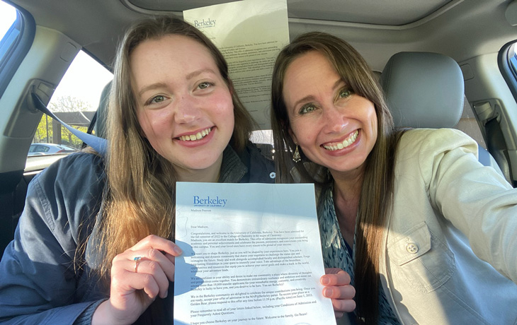 A photo of two women holding up a letter in a car.