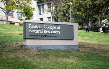 A sign reading Rausser College of Natural Resources on a hill in front of Hillgard Hall.