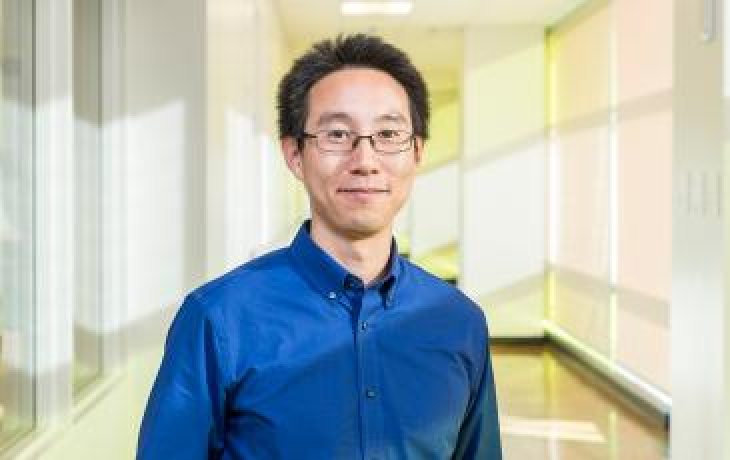 Image of a Patrick Shih in blue shirt standing in a hallway