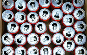 A photo of empty soda cans in a cardboard box.