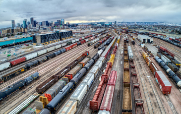 An aerial photo of several trains and rail cars at a depot outside of a city.