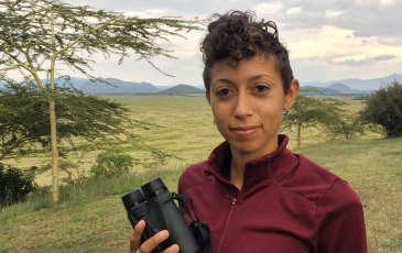 A photo of postdoctoral researcher Christine Wilkinson holding a pair of binoculars.