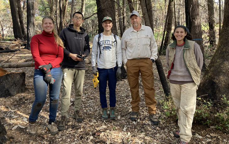 A group of students and ESPM professor Kip Will pose for a photo in a charred forest