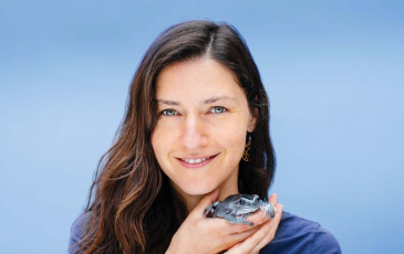 A headshot of Erica Bree Rosenblum holding a frog.