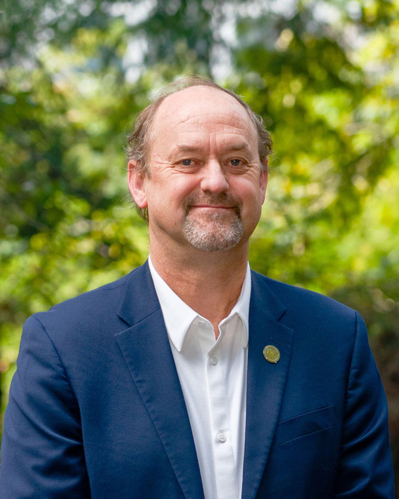 A photo of a man, David Ackerly, in a blue suit smiling at the camera.